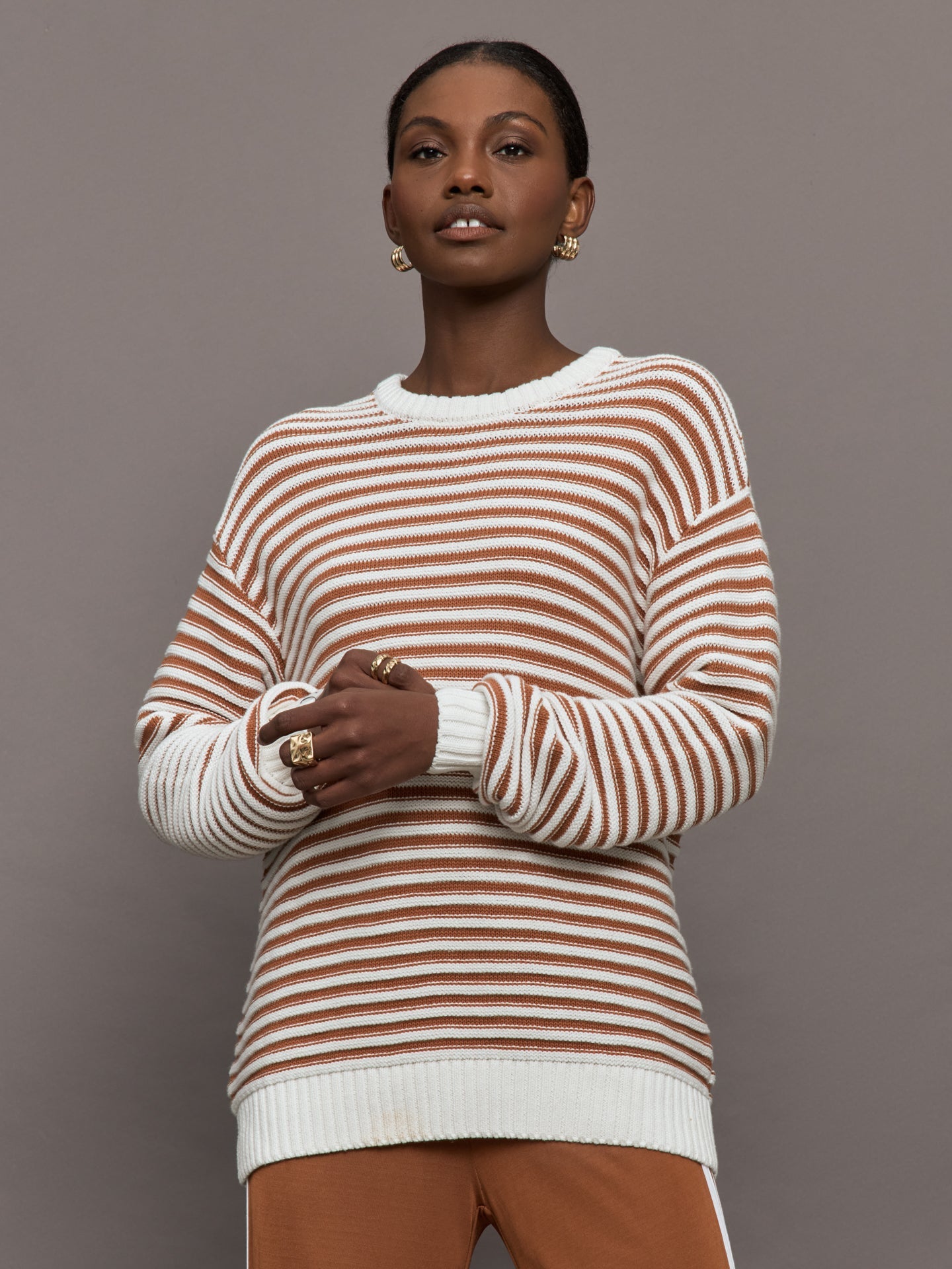 Model is wearing a brown/white horizontally striped oversized sweater.