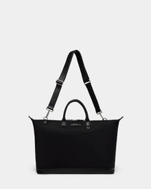 The Rudsak DUBLIN - 9324514 Black is a unisex, rectangular canvas leather bag with short handles, a long adjustable strap, silver hardware, and a minimalist design set against a plain white background.