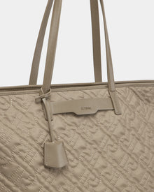 Close-up of the Rudsak LIVORNO - L325007 Almond tote bag featuring beige quilted monogram design, matching handles, geometric stitching, and a small attached leather tag.
