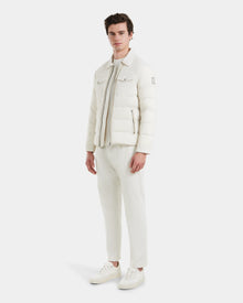 A man wears the Rudsak ORNO - 6124601 Vanilla jacket over a zip-up top, paired with white pants and sneakers, all set against a plain white background.