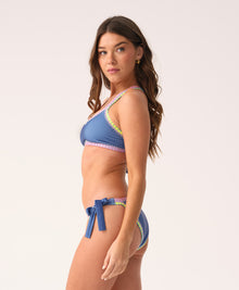 Woman wearing a blue bikini with colorful trim on a white background
