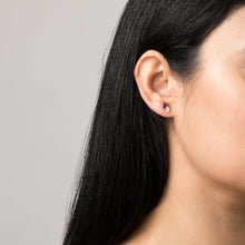 Model. Close-up of an ear with a small earring on a gray background