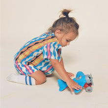 Child wearing short-sleeve button-down shirt with abstract wavy stripes in blue, pink, yellow, and white.