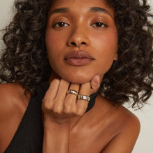 Model. Woman with curly hair wearing a black top against a neutral background