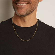 Man wearing a gold chain necklace against a neutral background