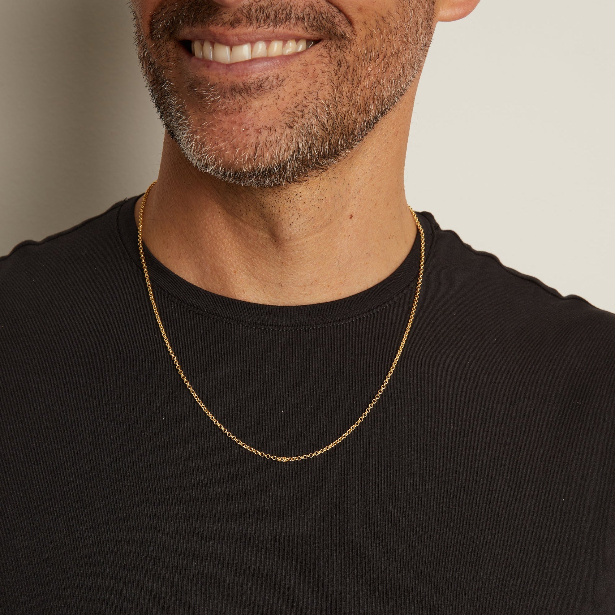 Man wearing a gold chain necklace against a neutral background