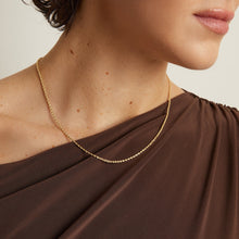 Model. Gold necklace on a person wearing a brown garment