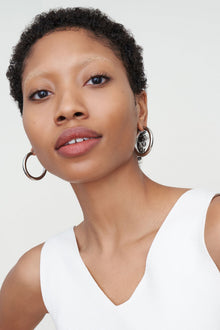 Detail image of a woman standing wearing the Claressa Earrrings Medium in Silver | Exclude