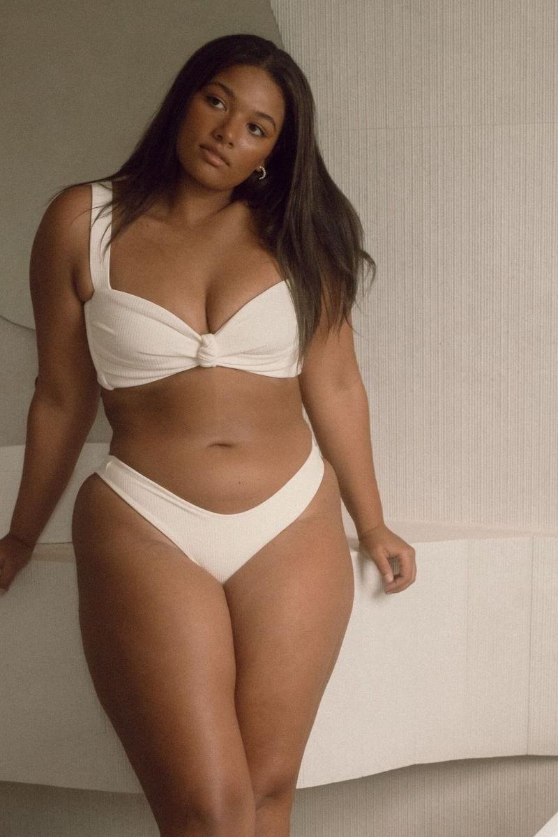 Cream ribbed bikini bottom with wide waistband, displayed on model wearing matching top.