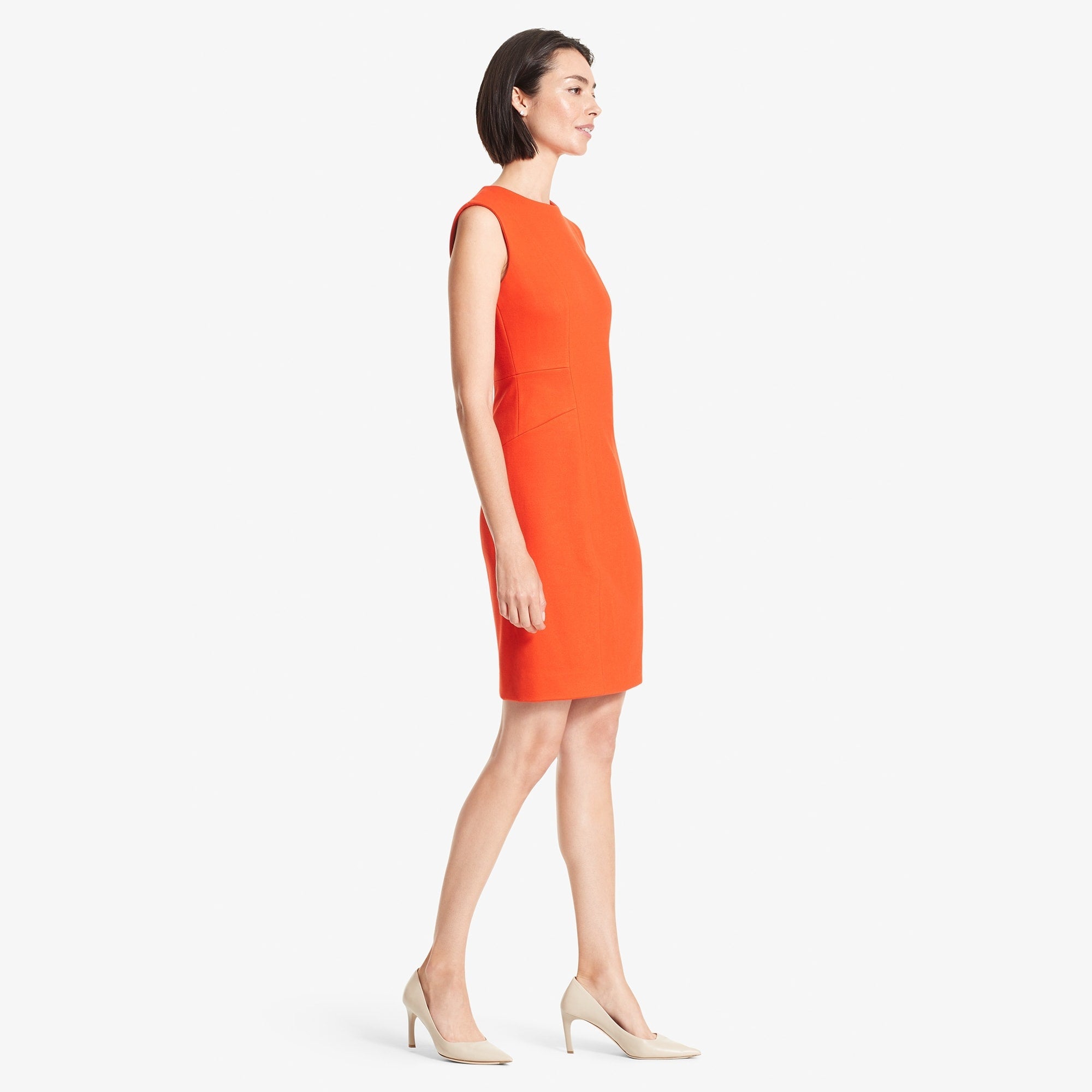 Side image of a woman standing wearing the Giovanna dress in Tangerine | Exclude