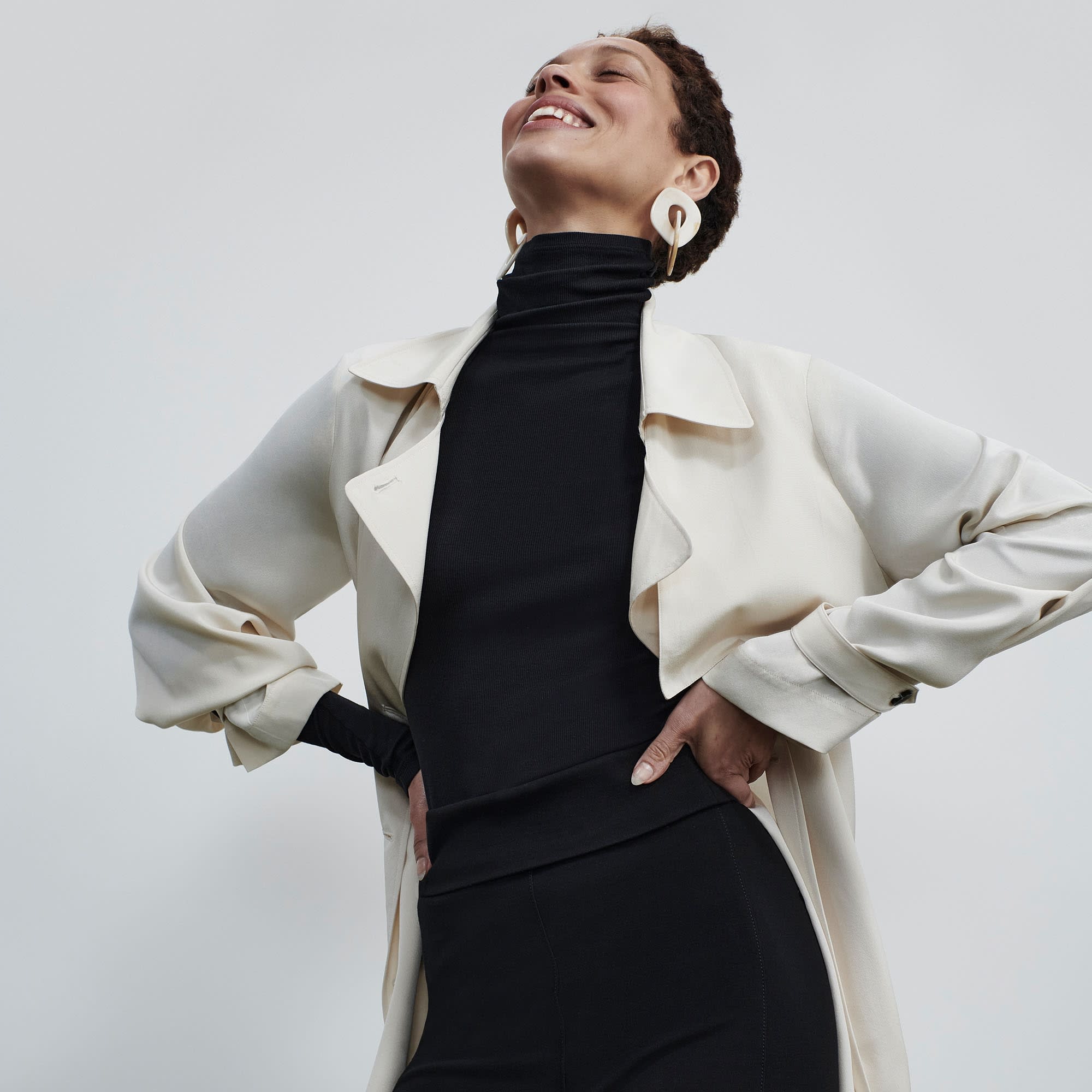 Front image of a woman standing wearing the axam top in black | Exclude