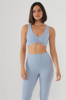 Light blue ribbed bikini top with V-neckline and twisted front detail, worn with matching high-waisted bottoms.