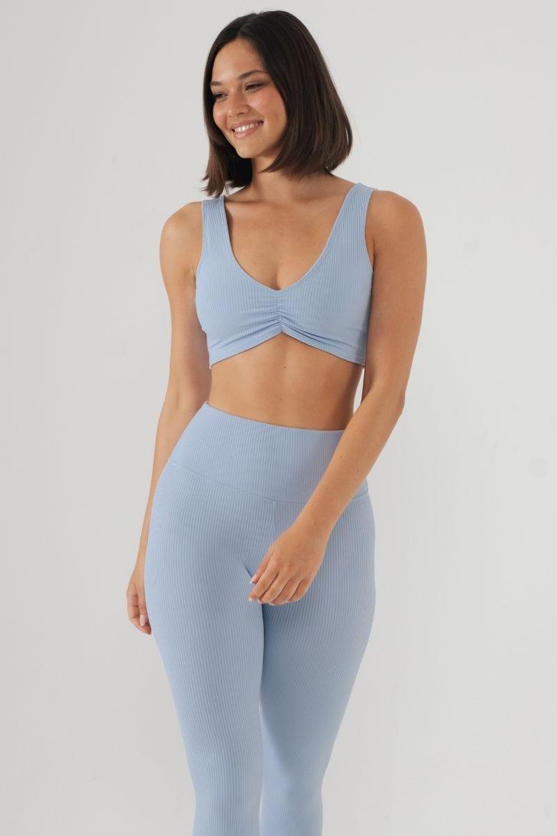 Light blue ribbed bikini top with V-neckline and ruched center detail on model wearing matching bottoms.