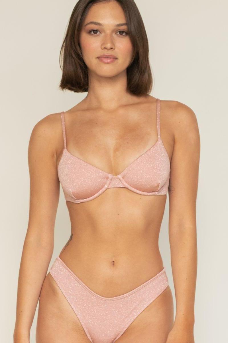 Pink sparkle bikini bottom with low-rise waistband and shimmer finish shown on model.