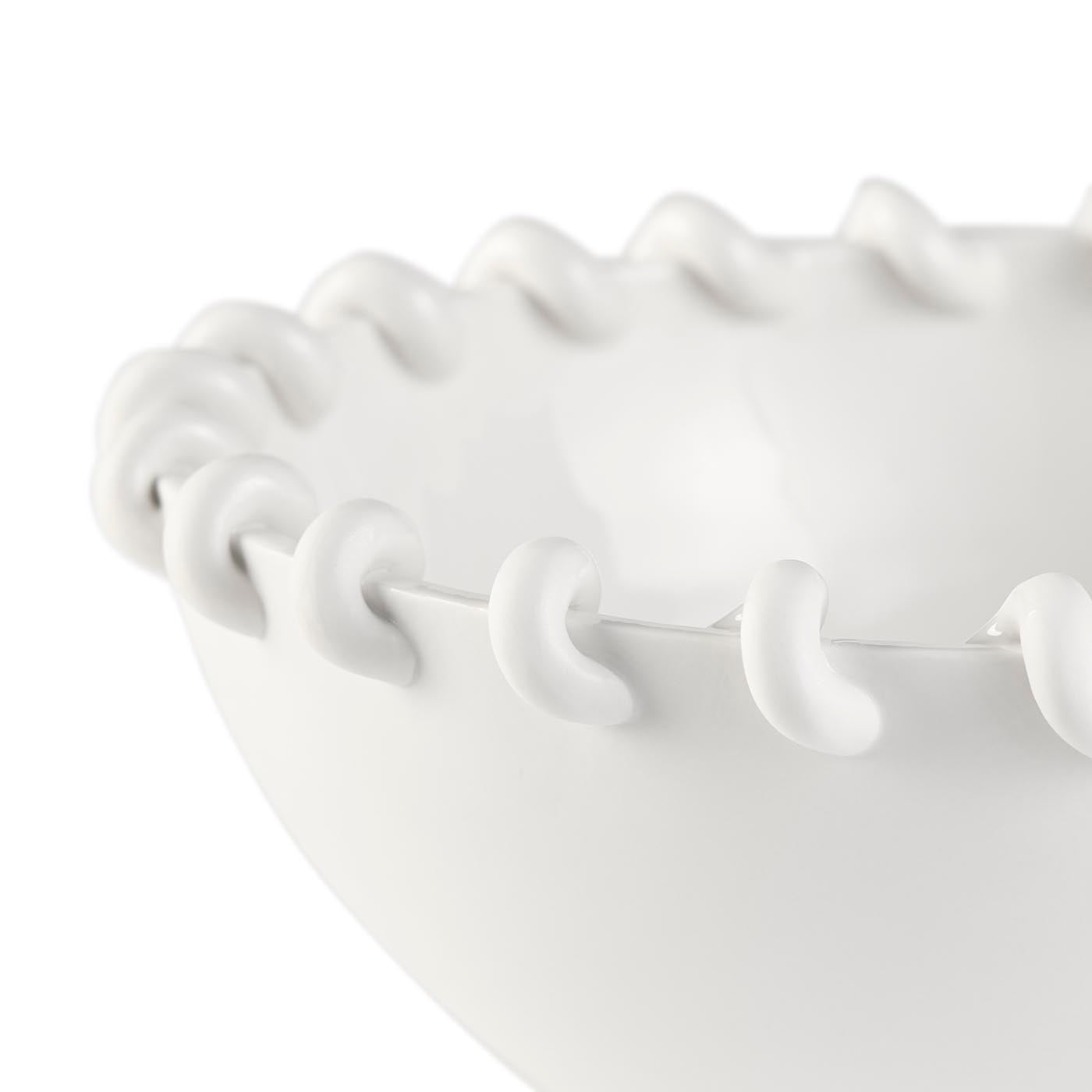 Close-up of a white ceramic bowl with textured rim on a white background