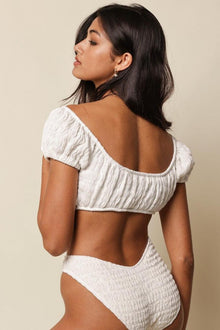 White textured bikini top with short puffed sleeves and scoop neckline, shown from back view on model.