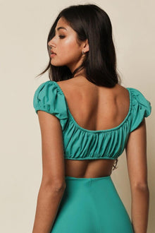 Teal bikini top with puffed short sleeves and ruched fabric detail worn by a model shown from behind.