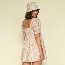 Cream bucket hat with pink floral pattern, shown worn with matching floral dress.