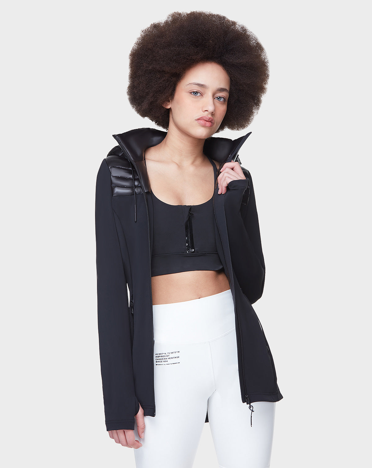 A woman poses for a photo in the Rudsak CAMIRA - 8122011 BLACK activewear jacket, featuring waterproof zippers.