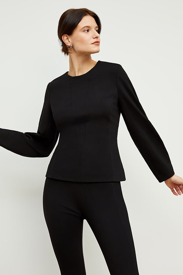 Front image of a woman standing wearing the rashida top in black | Exclude