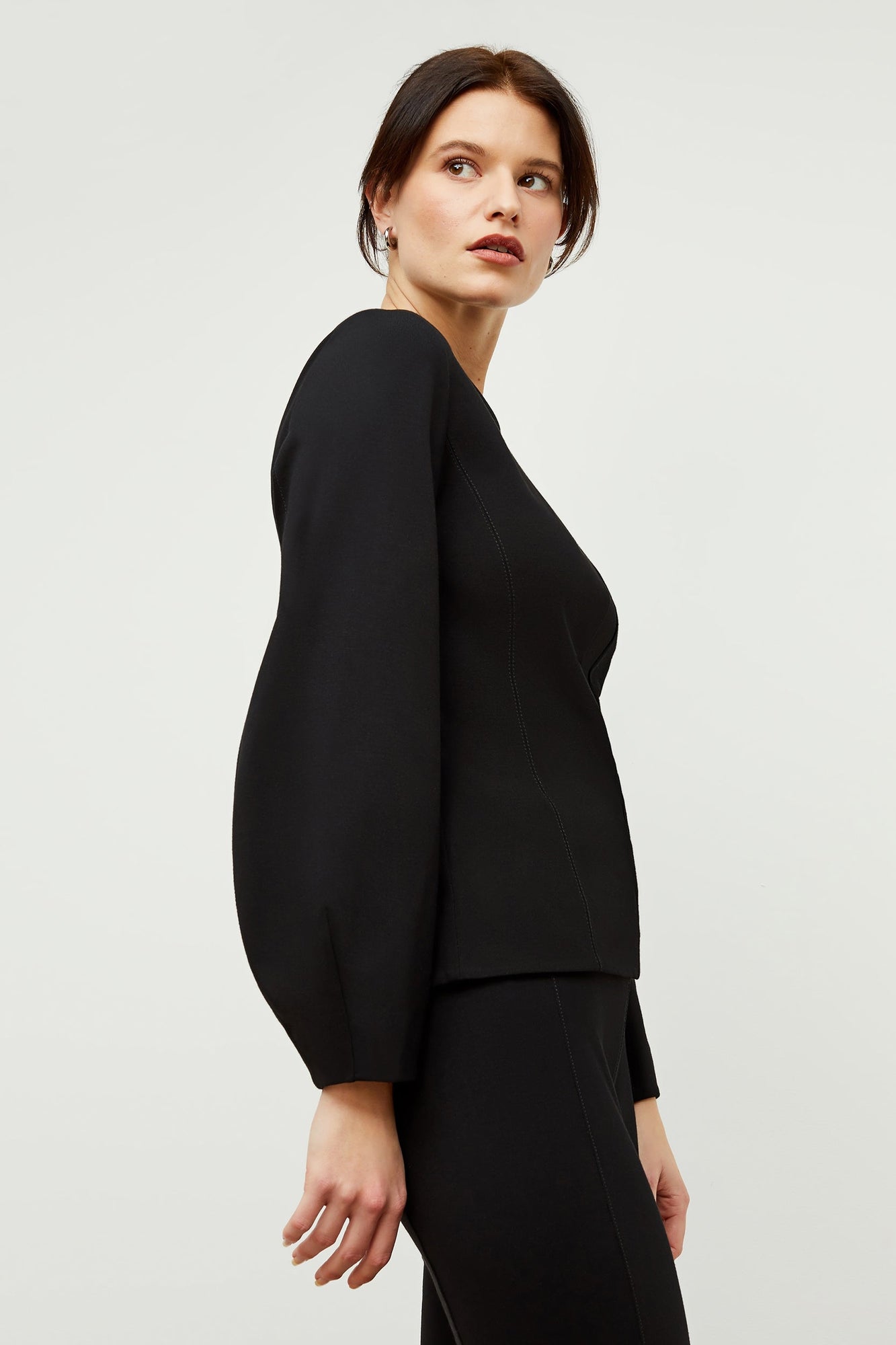 Side image of a woman standing wearing the rashida top in black | Grid Hover | Exclude